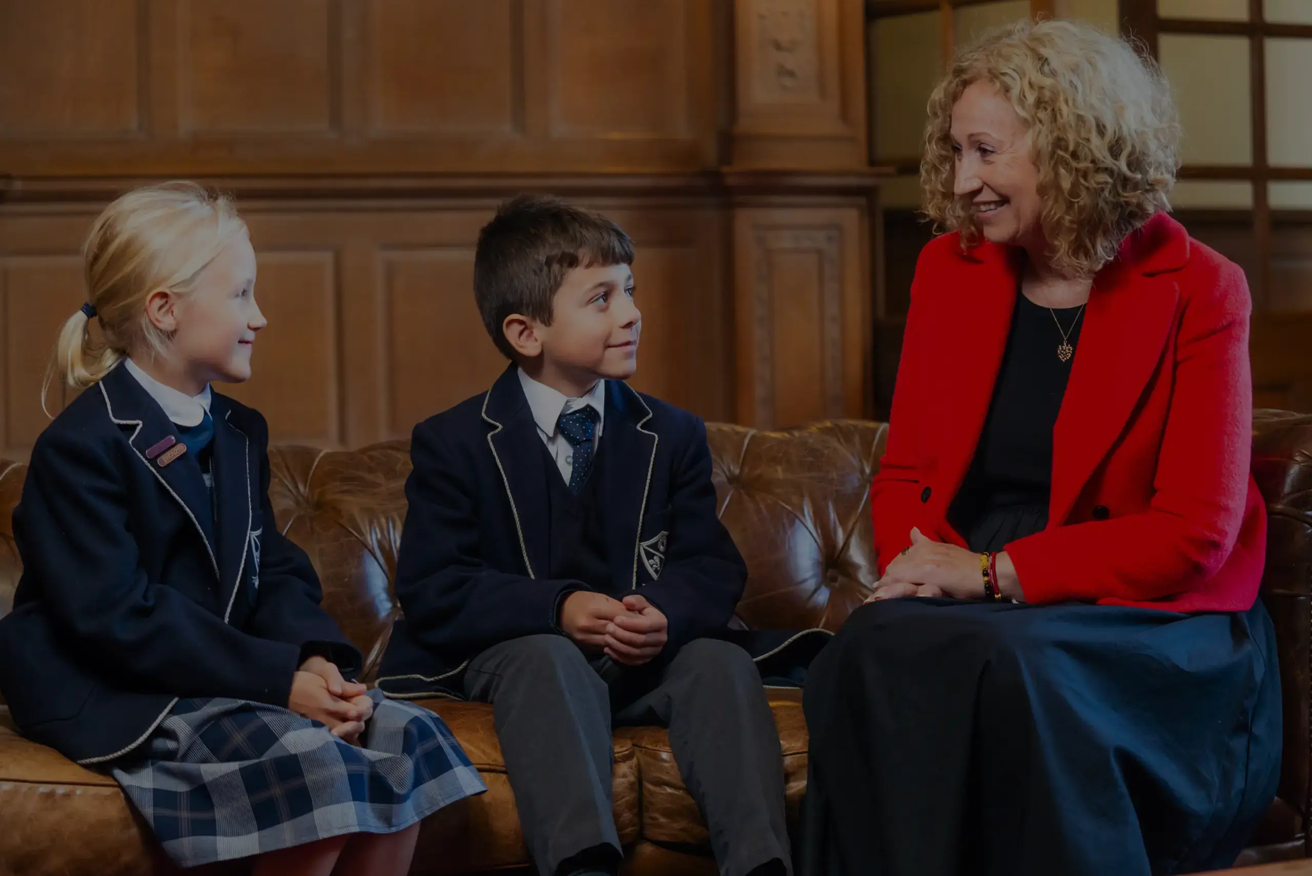 Head of school chatting with students on sofa