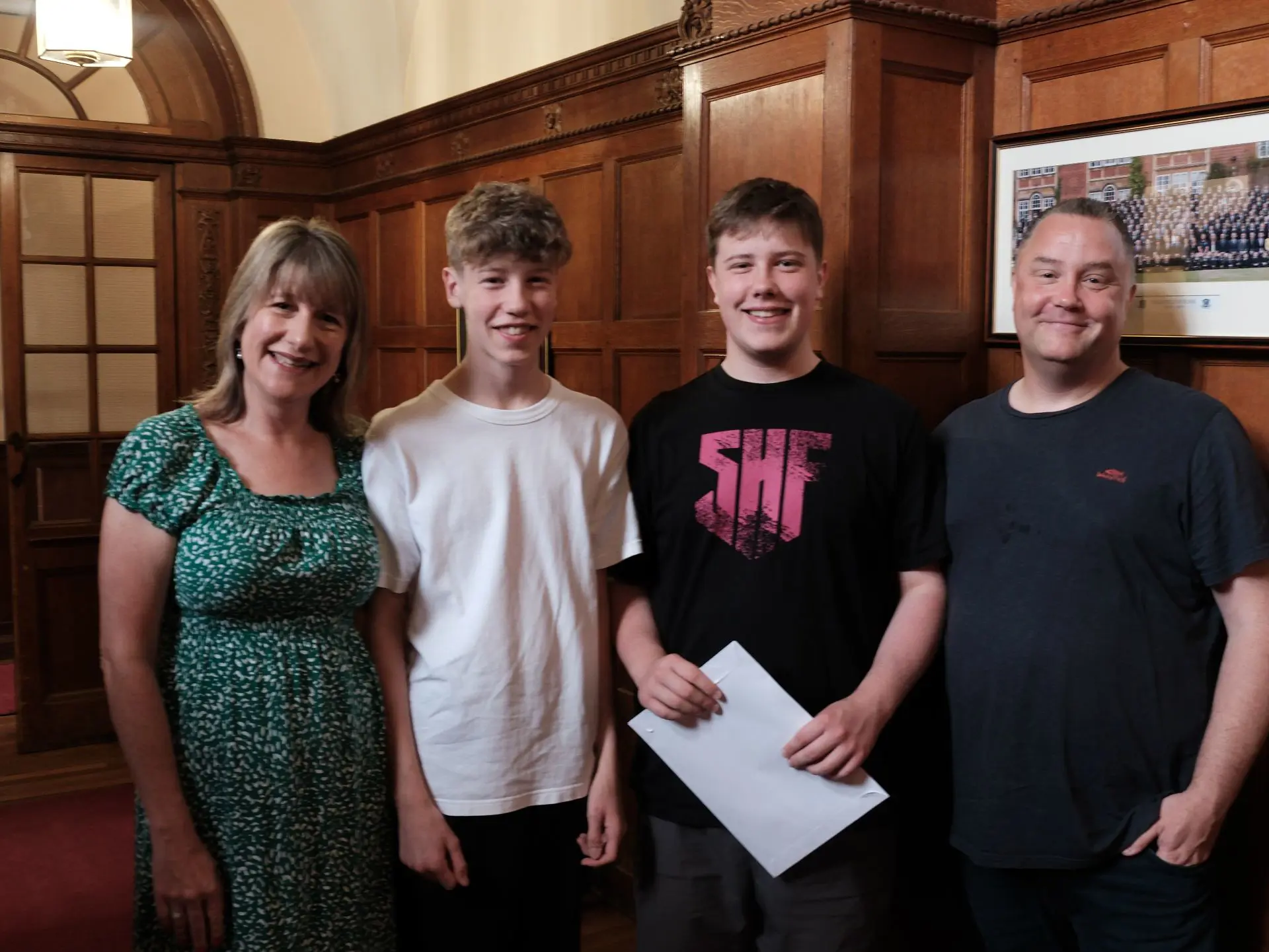 Family of four standing together in wood-paneled room