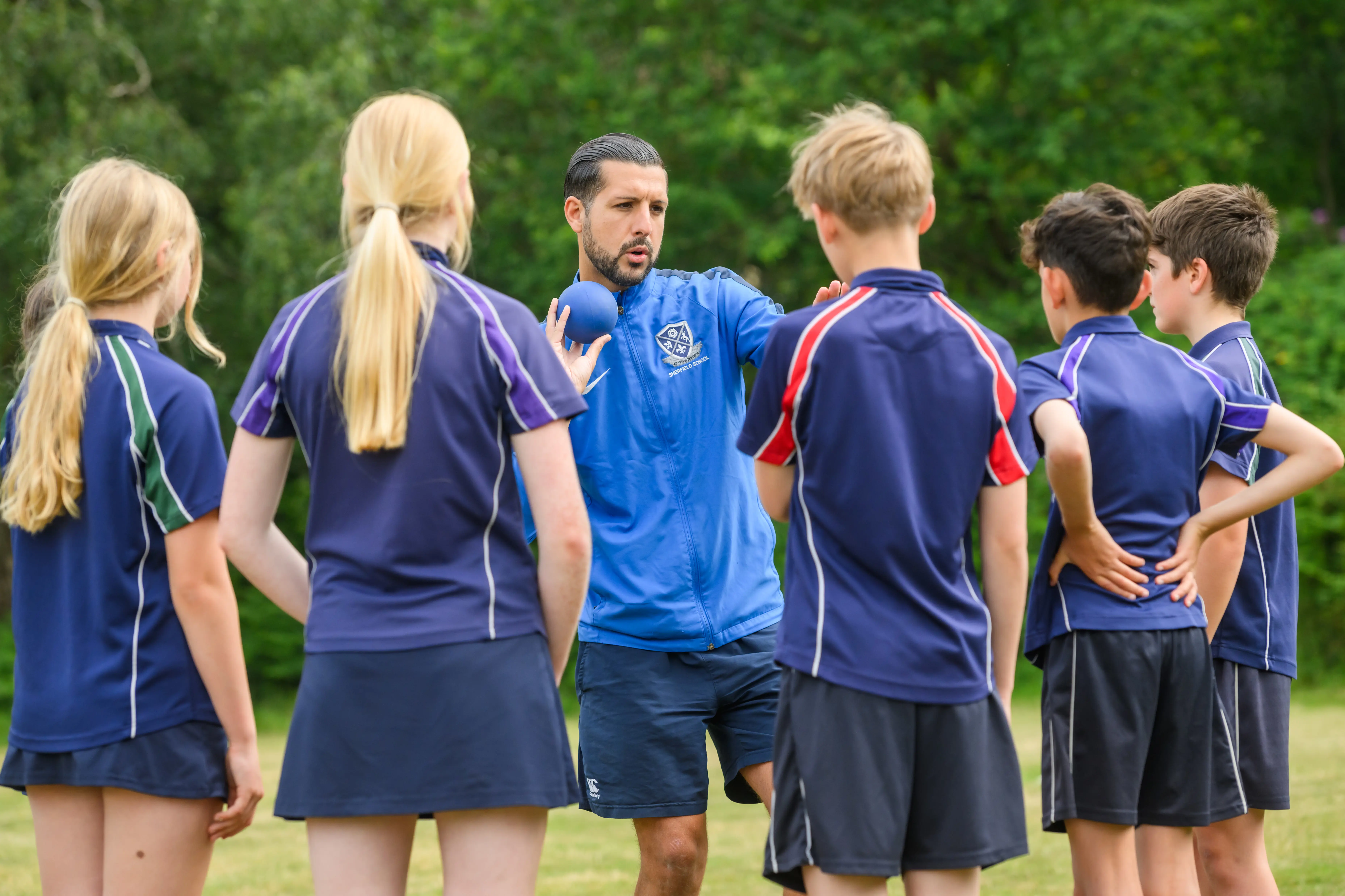 Shotput instructor demonstrating technique to students