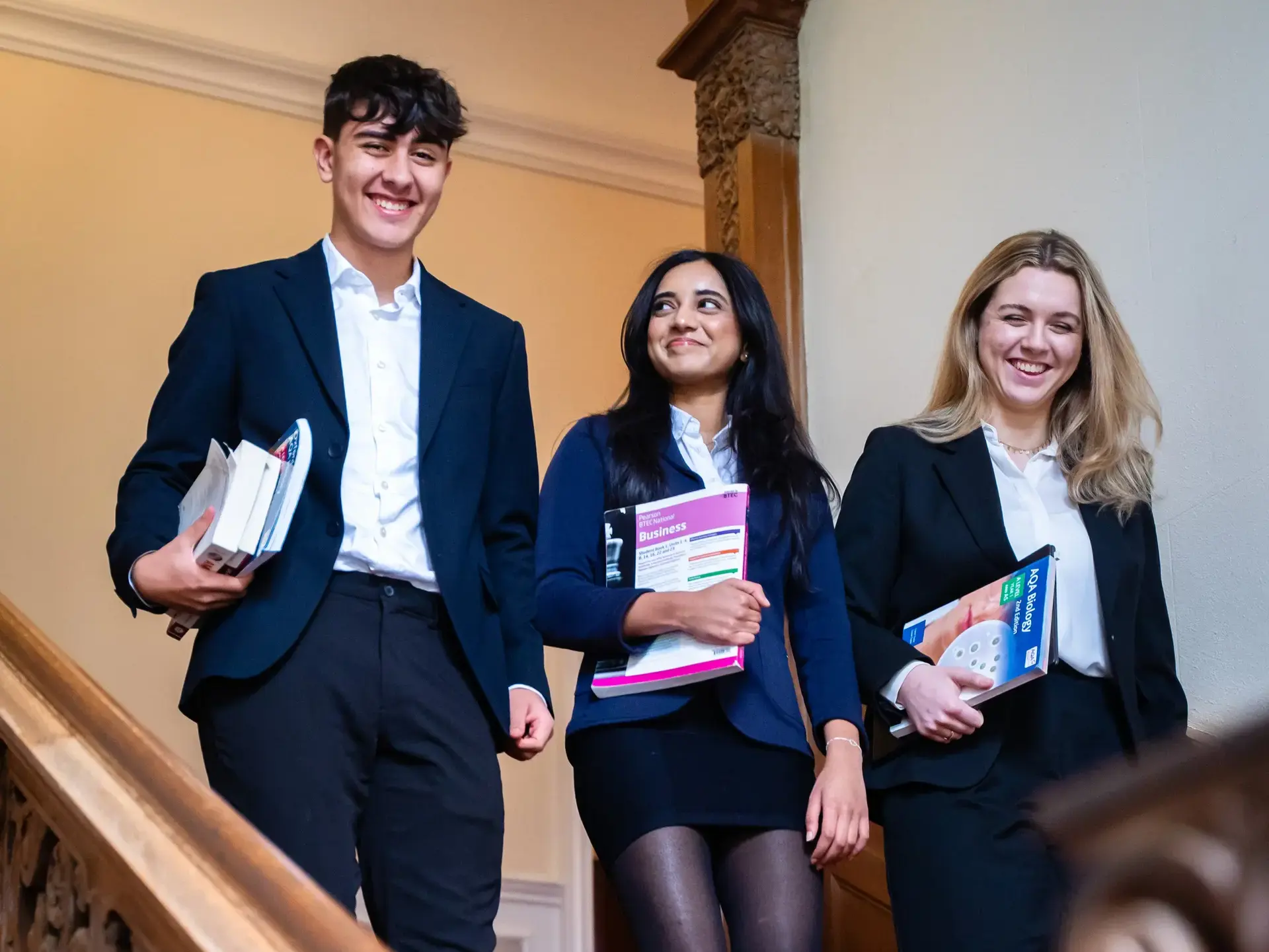 Three Sixth Formers walking down stairs together