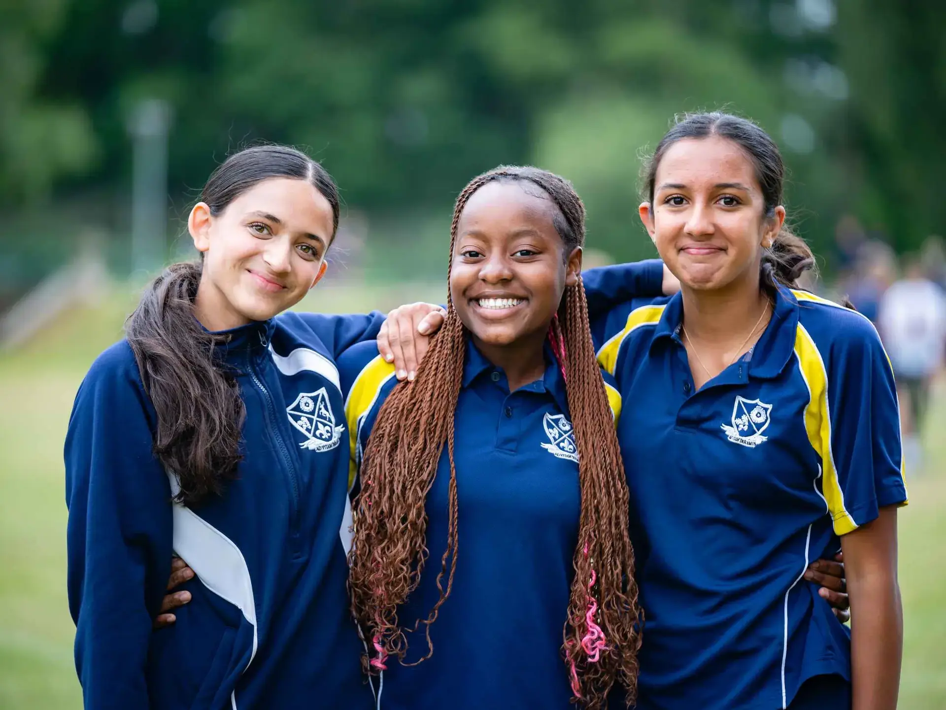 Three students standing together, wearing PE kits