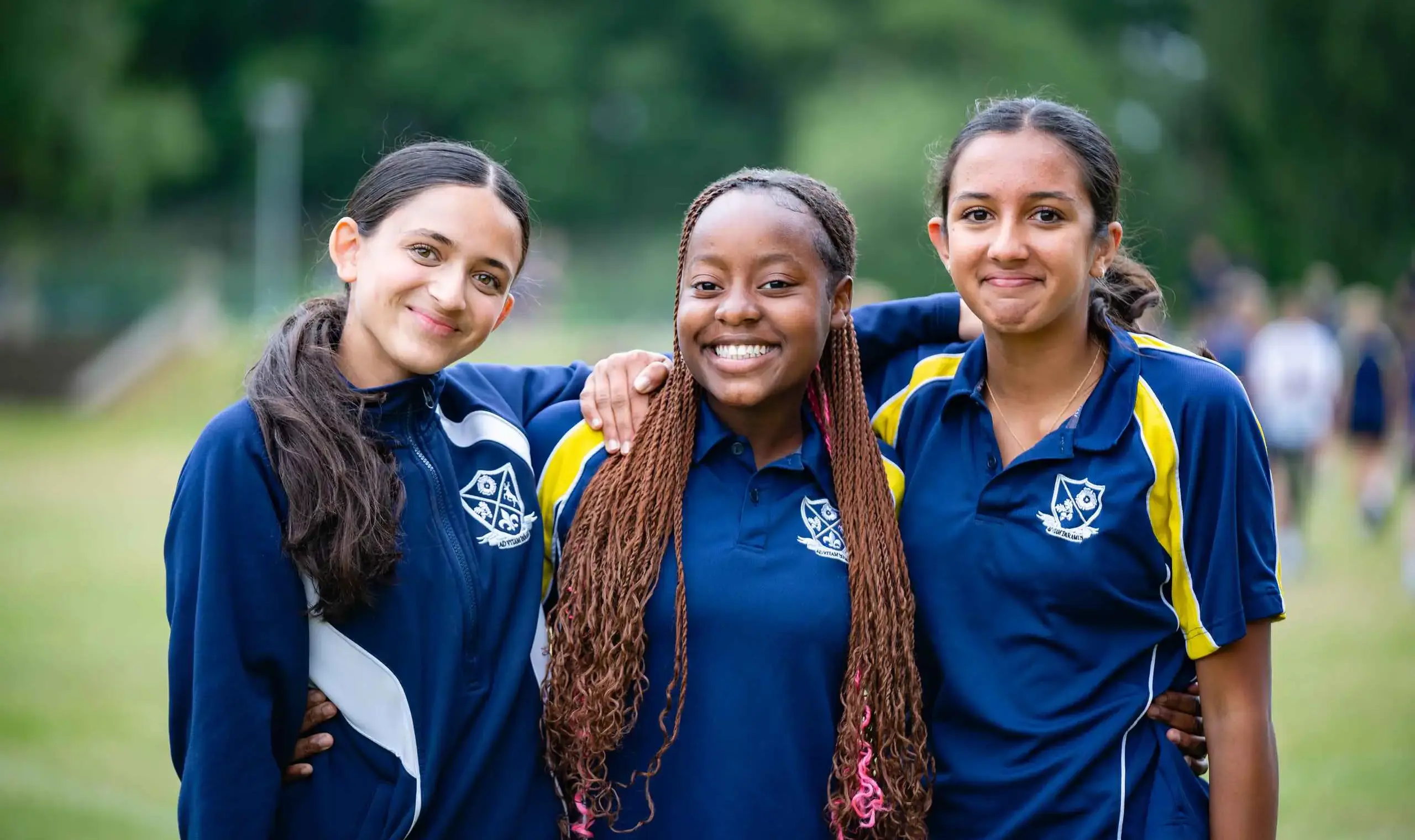 Three students in PE kit smiling together