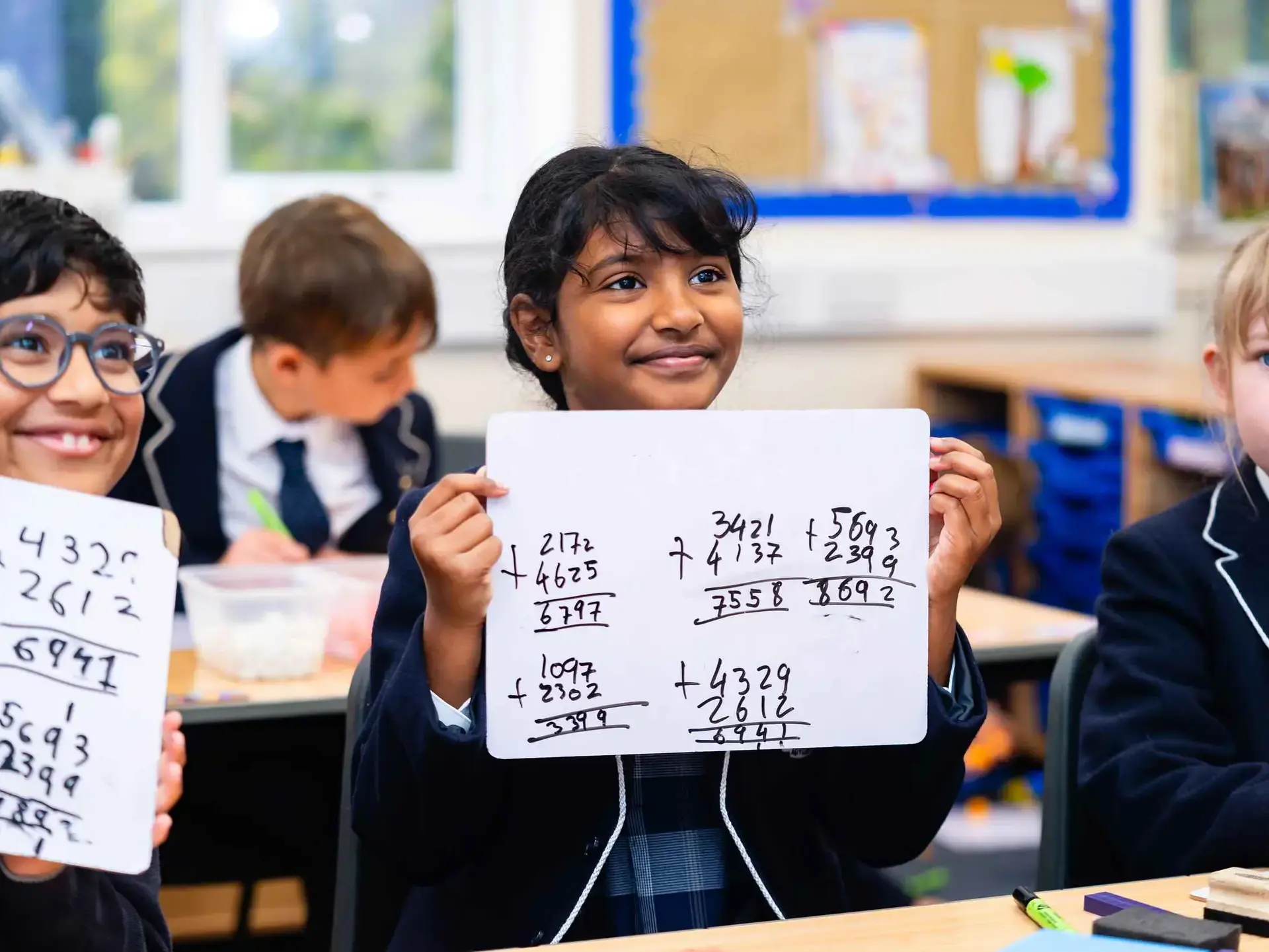 Students showing maths working out on whiteboards