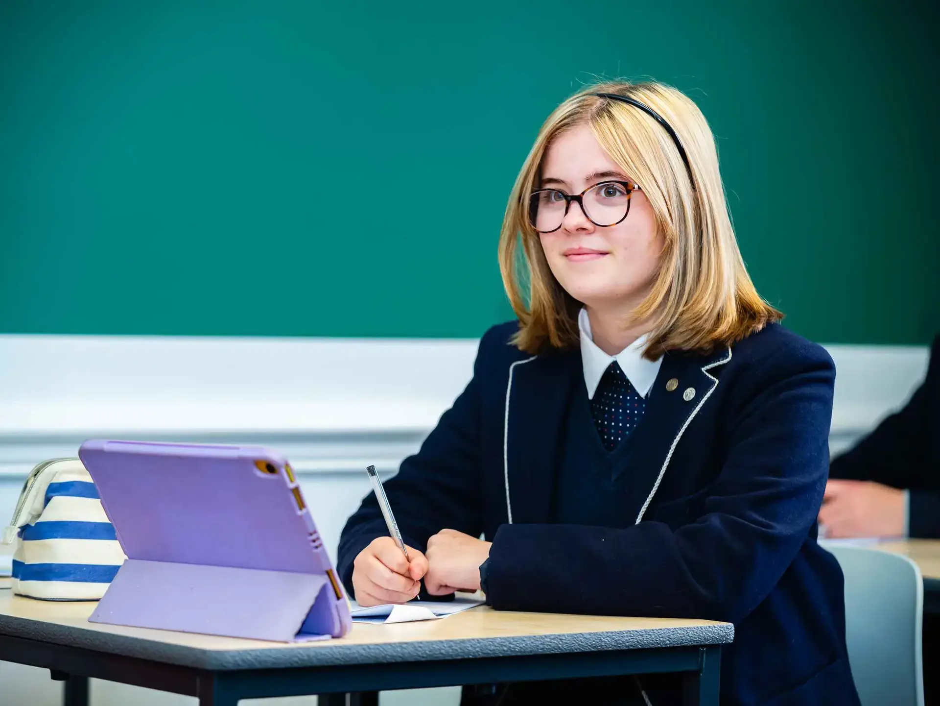 Student working at desk with tablet and notebook