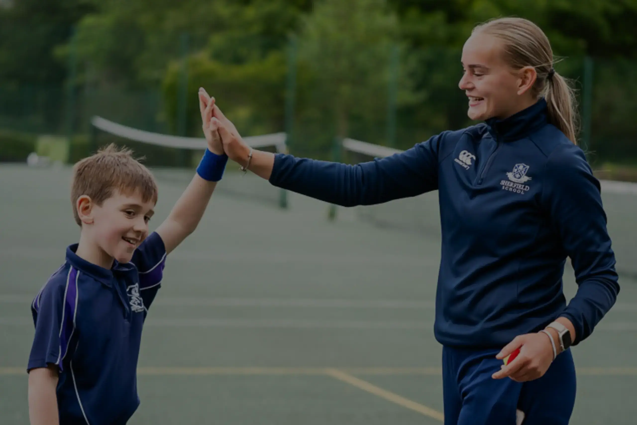 Tennis teacher and student high-fiving