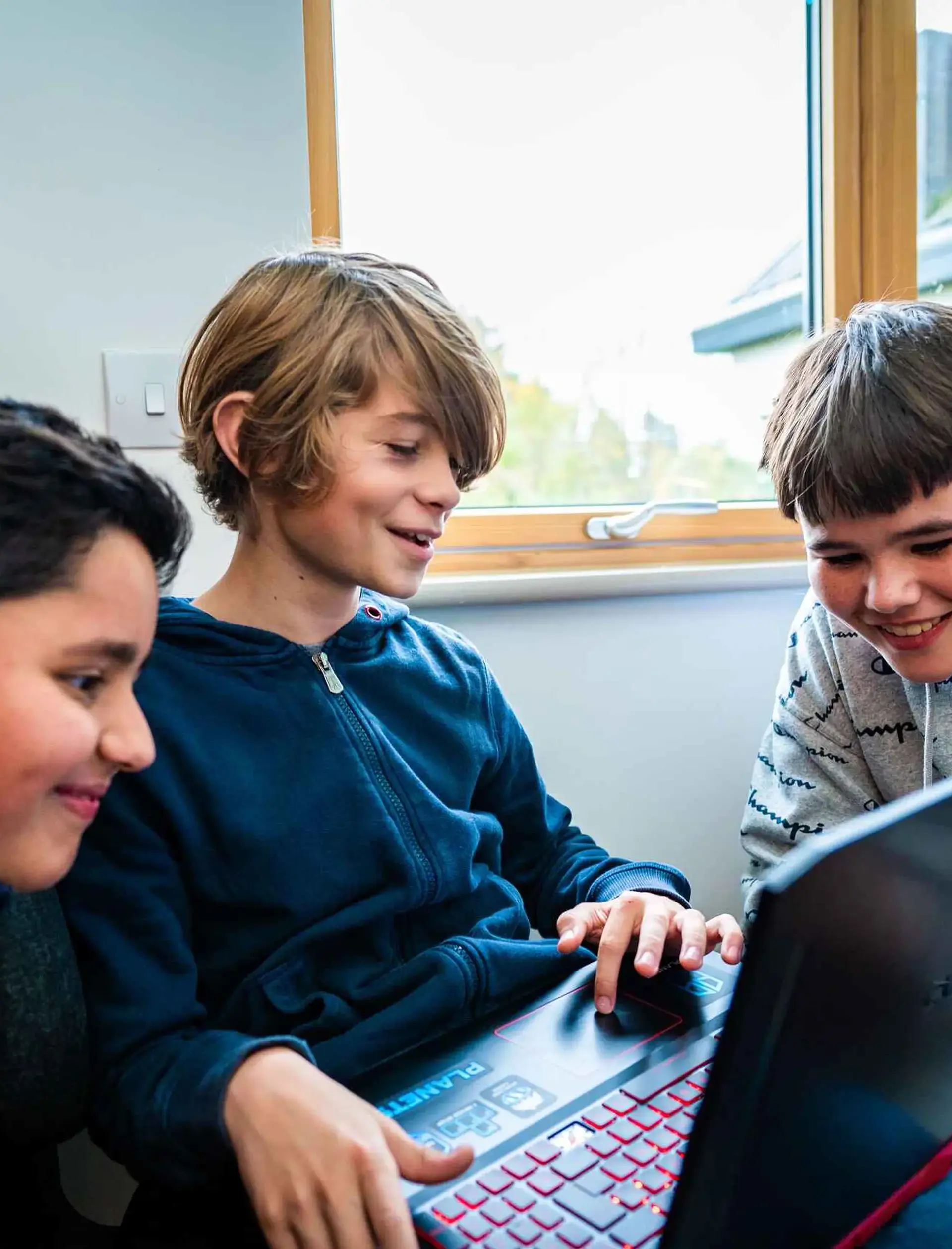 Three students crowding around a laptop and chatting
