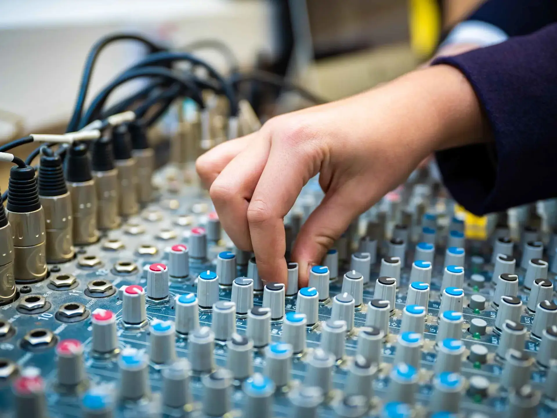 Hand turns dial on sound production equipment