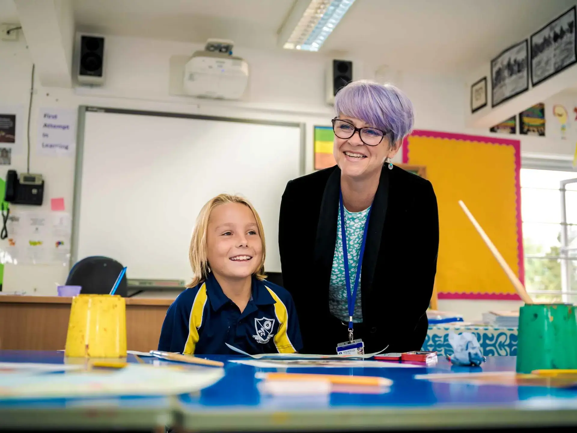 Student and teacher smiling behind desk