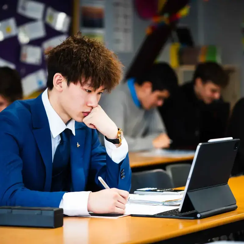 Student glancing at tablet while taking notes