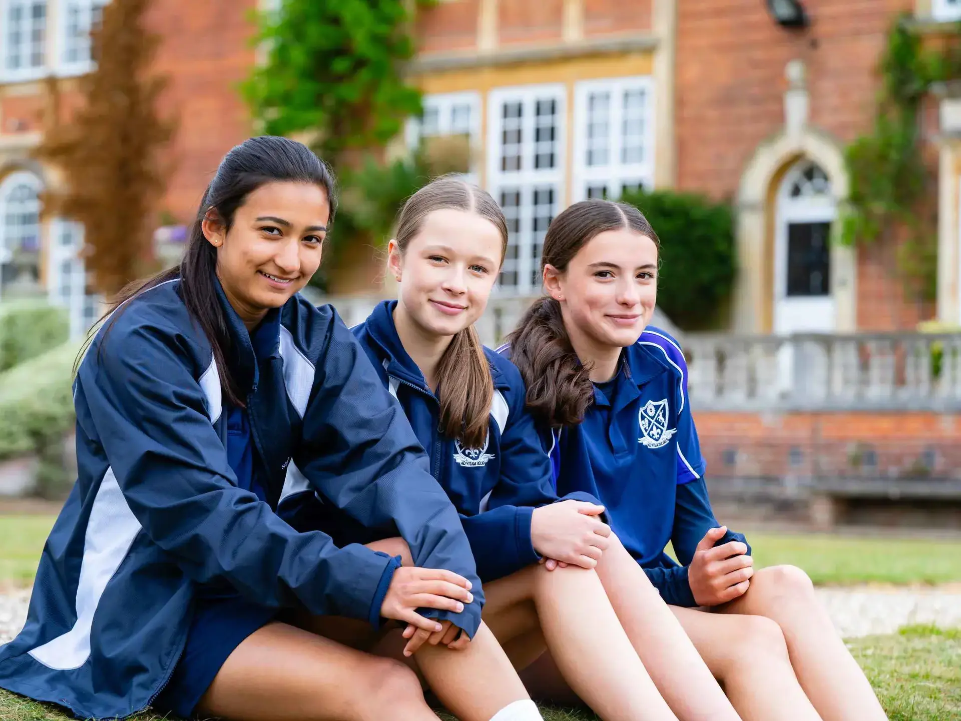 Students sitting outside, smiling for camera