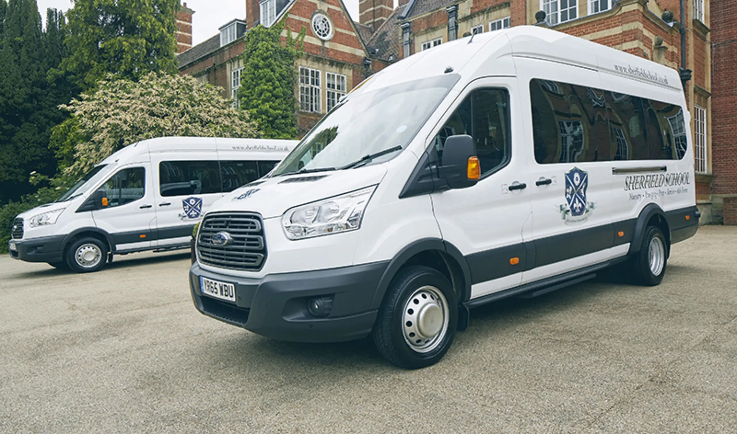 Two Sherfield minibuses parked outside the school