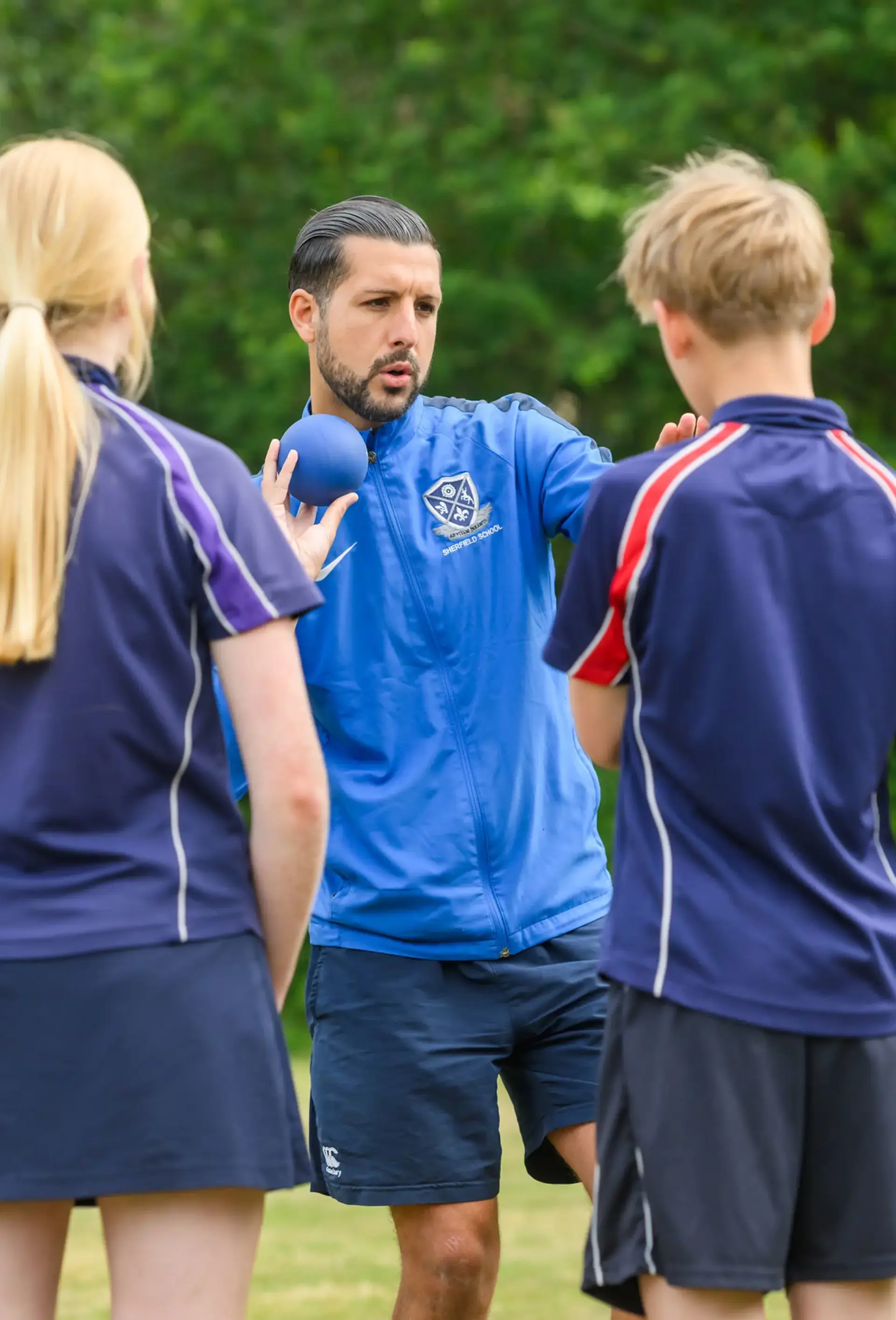 Shotput instructor demonstrating technique to students