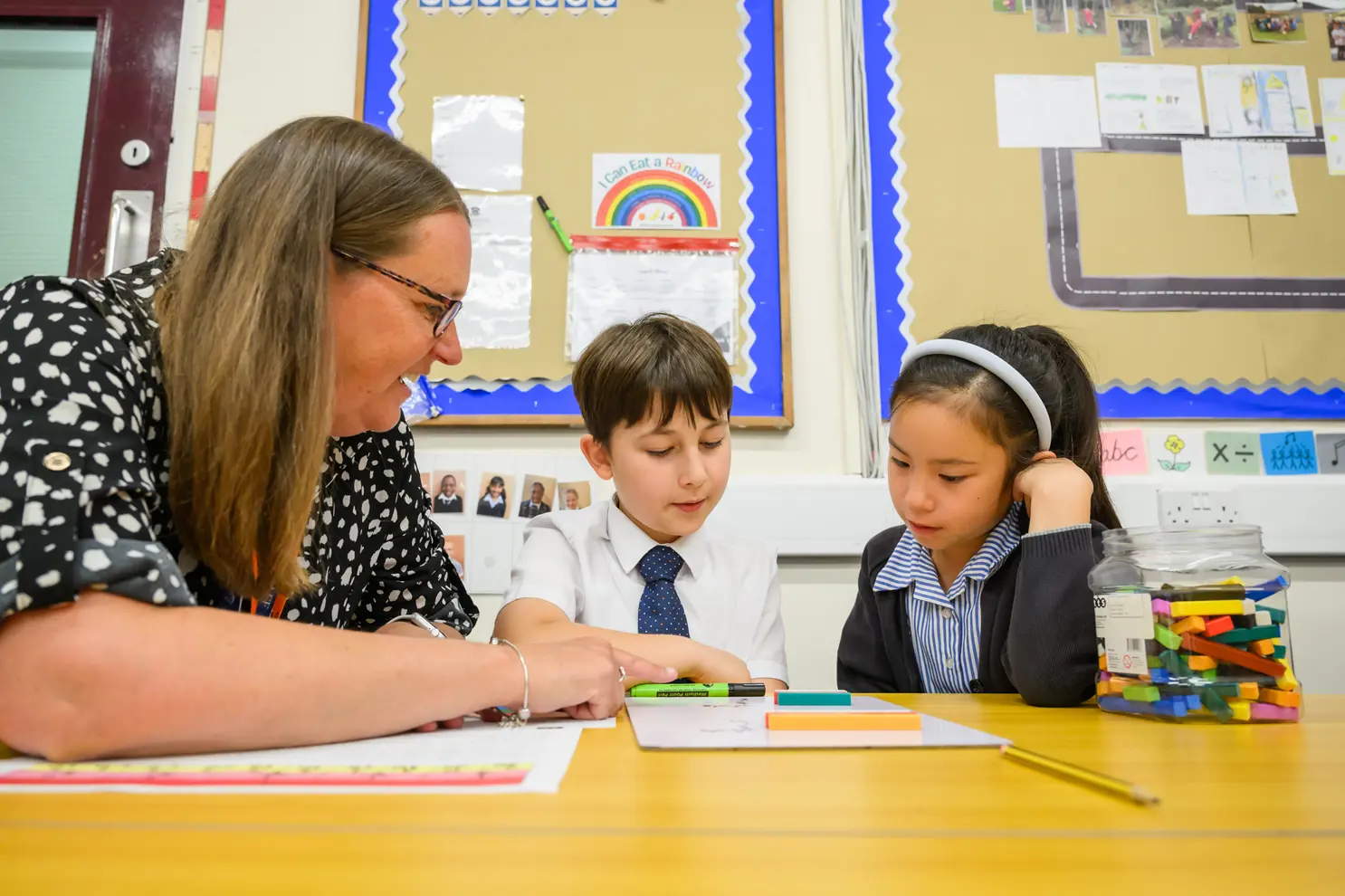 Two students and a teacher working at table together